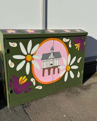 Utility cabinet on Abbey Street painted with the Old Grammar School in a pink roundel and large white daisies