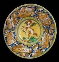 Italian Renaissance maiolica dish with a cupid drawing a bow at its centre and a blue rim painted with armour, drums and an ‘S.P.Q.R.’ tablet.