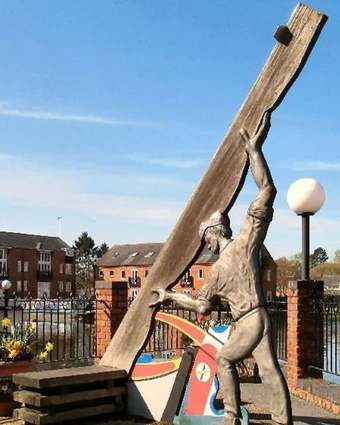 Frank the Plank sculpture of a man raising a wooden plank at Union Wharf canal basin, Market Harborough