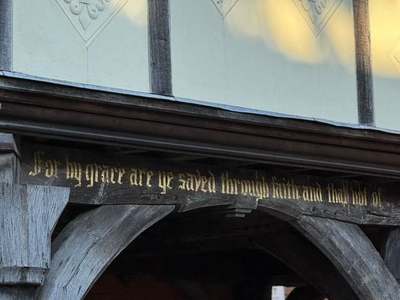 Gilded inscription on the carved timber beam of The Old Grammar School, Market Harborough, beneath decorated plaster panels