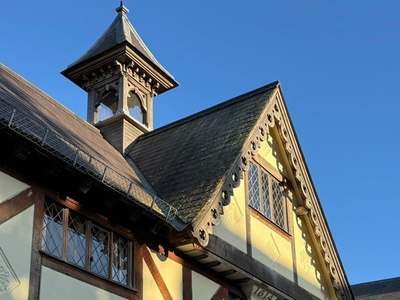 The Old Grammar School in Market Harborough: timber-framed gable with a cupola, lit by golden evening sun against a blue sky.
