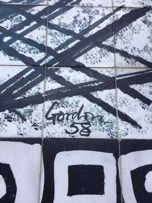Detail of a 1950s ceramic tile mural with bold black brushstrokes and the painted signature ‘Gordon 58’