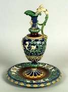 Victorian majolica ewer in cobalt blue and green with raised white figures, standing in a matching round basin.